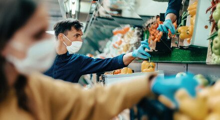 shoppers in protective masks choosing fruit in the supermarket