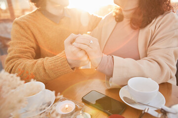 Close-up of young romantic couple holding hands and enjoying each other during their date in restaurant