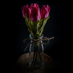 Bouquet of tulip flowers in a glass bottle isolated against a black background.