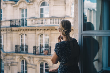 Naklejka na ściany i meble Woman overlooking Paris in Window