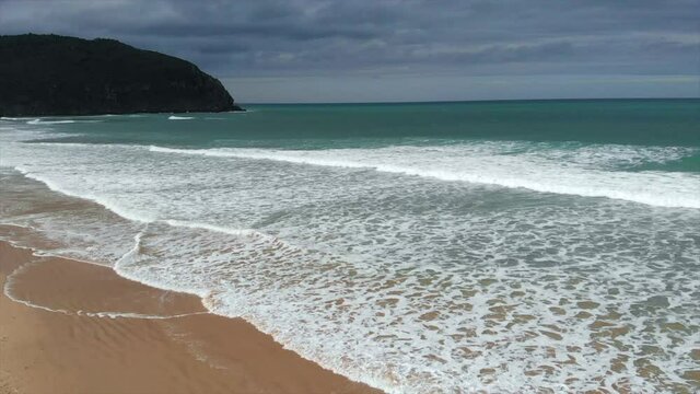 playa con olas y cielo con nubes