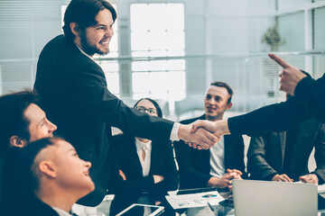 smiling business people shaking hands over an office Desk