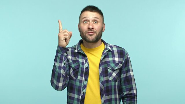 Slow motion of handsome caucasian man standing pensive, pucker lips and touching beard thoughtful face, raising finger when pitching an idea, found answer, standing over blue background