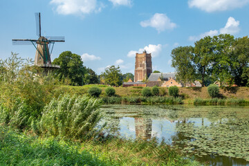 The church and historic dutch windmill in Woudrichem, The Netherlands, with ramparts and a pool...