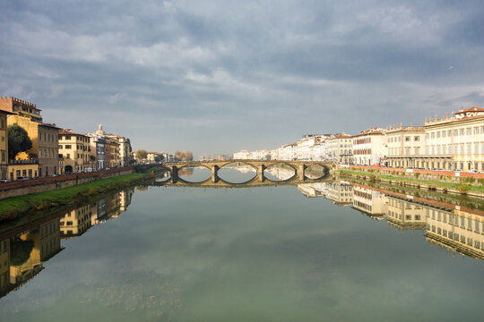 The Arno river in Florence on a windless day, with reflections of the houses on both sides in the water