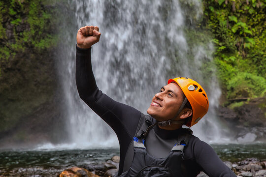 Hispanic Cheerful Rock Climber In A Helmet Hat And Safety Harness Celebrating An Achievement