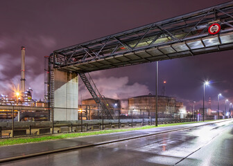 Fototapeta na wymiar Rainy night scene with pipeline overpass at petrochemical production plant, port of Antwerp, Belgium.