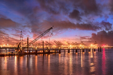 Industrial landscape at colorful sunset with pier and container terminal on the background, Port of Antwerp.