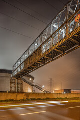 Night scene industrial area with illuminated pipeline overpass, port of Antwerp, Belgium.