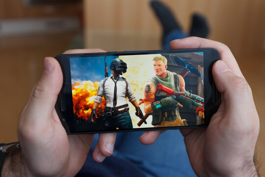 LOS ANGELES, CALIFORNIA - JUNE 3, 2019: Lying Man holding a smartphone and compares PUBG and Fortnite games on the smartphone screen. An illustrative editorial image.