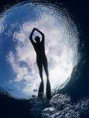 free diver swimming underwater silhouette with sky and clouds in picture