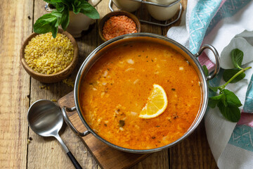 Turkish cuisine. Traditional soup with rice, lentils and mint on a rustic table.