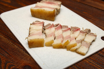 Dill, slices of salted pork lard, piece of lard, slices of bread on pink plastic cutting board isolated on white background. Top view
