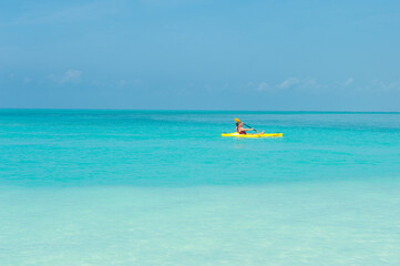 Fototapeta na wymiar Elderly woman swimming on yellow canoe boat and kayak in turquoise ocean