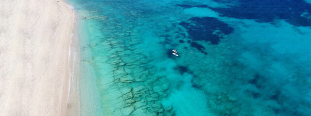 Aerial drone ultra wide photo of couple practice SUP or Stand Up Paddle board in tropical exotic bay with turquoise sea