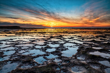 beautiful sunset over the ocean with rocky beach and tidal pools in the foreground
