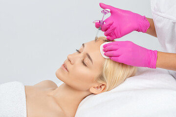 Cosmetologist makes rejuvenating anti wrinkle injections on the face of a beautiful woman. Female...