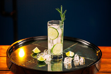 Fresh gin tonic cocktail with rosemary and lime on the round tray