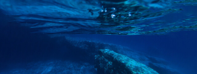 Obraz na płótnie Canvas Underwater ultra wide photo of deep blue paradise rocky bay