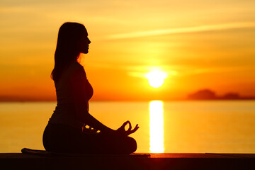 Silhouette of a woman doing yoga exercise at sunset