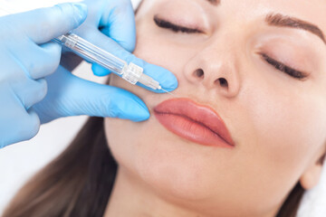 Cosmetologist does injections for lips augmentation and anti wrinkle in the nasolabial folds of a...