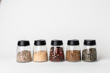 Salt and pepper grinders. Dried whole seed of black pepper and white coarse sea salt isolated on a...