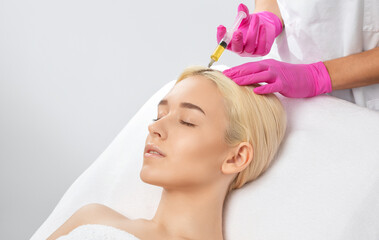Cosmetologist does prp therapy against hair loss and anti-dandruff of a beautiful brunette woman in...