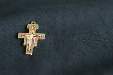 Tło - franciszkański krzyż San Damiano na tle ciemnej tkaniny.