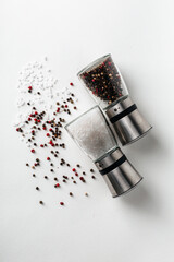 Salt and pepper grinders. Dried whole seed of black pepper and white coarse sea salt isolated on a...