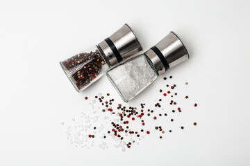 Salt and pepper grinders. Dried whole seed of black pepper and white coarse sea salt isolated on a...