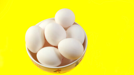 Organic white chicken eggs isolated on yellow background.