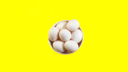 Organic white chicken eggs isolated on yellow background.