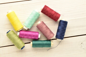 Several spools of colored thread, close-up, on a wooden table.