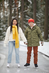 Portrait of happy couple smiling at camera while skating on skating rink together in the park