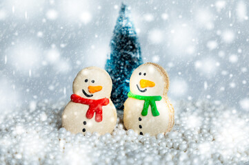 Winter scene with two snowman macaroons, christmas trees and snow