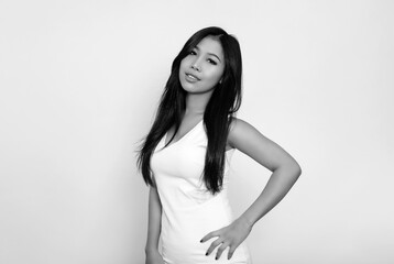 Beautiful asian woman with long black hair posing in dress on grey background