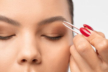 Makeup artist combs  and plucks eyebrows after dyeing in a beauty salon.Professional makeup and...