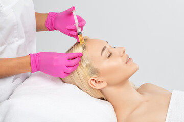 Cosmetologist does prp therapy against hair loss and anti-dandruff of a beautiful brunette woman in...