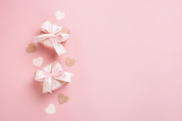 Fototapeta na wymiar Gift boxes with pink ribbon and hearts on pastel pink background. Valentines day composition with free space. Top view, flat lay.