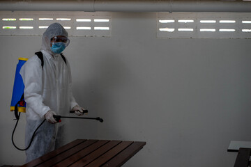 health care worker in white jumpsuit and protective face mask using spraying machine to disinfect virus pandemic.  Health care and midicine concept. New normal social distancing concept.