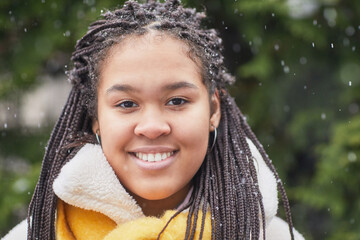 Portrait of African young woman with beautiful hairstyle smiling at camera standing outdoors