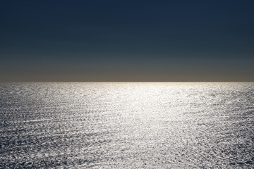 abstract view of ocean water with glistening sunlight and orange and blue sky