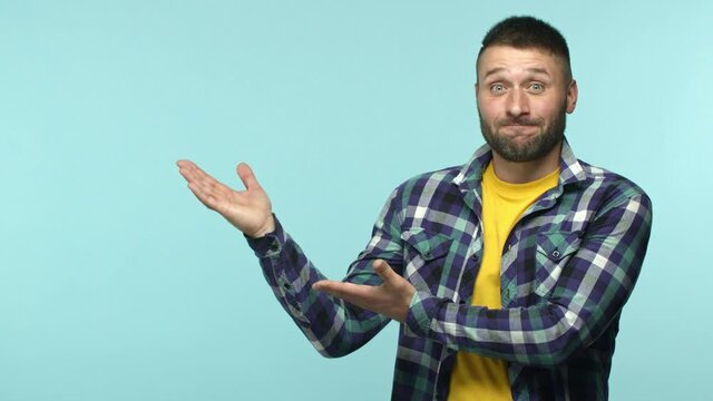 Slow motion of handsome adult man with beard and blue eyes wearing casual clothes, demonstrate promo offer, pointing hands left and smiling, recommending product, blue background