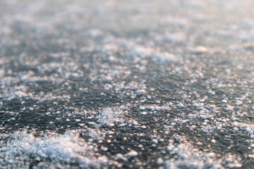 Frozen ice cold deep lake surface with snow macro sparkling in orange sunset light background