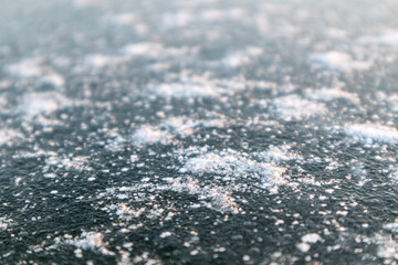Frozen ice cold deep lake surface covered with snow close-up sparkling in orange sunset light. Blurred background