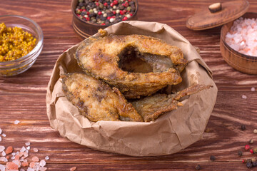 Pieces of fried carp in a paper bag on a wooden table. Food delivery