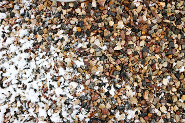 colorful stones powdered by first snow close up background 