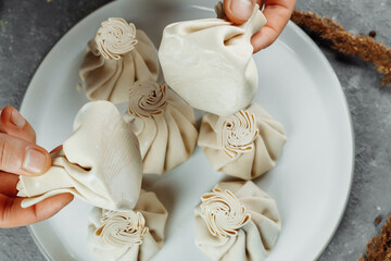 the hand holds the chikali by the tail. Khinkali in a Georgian restaurant in hand. Georgian cuisine