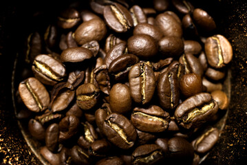 Moody tone, close-up view of roasted coffee bean inside grinder machine.