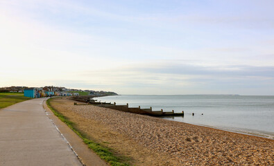 Stony beach with breakwater and beach huts in the distance
